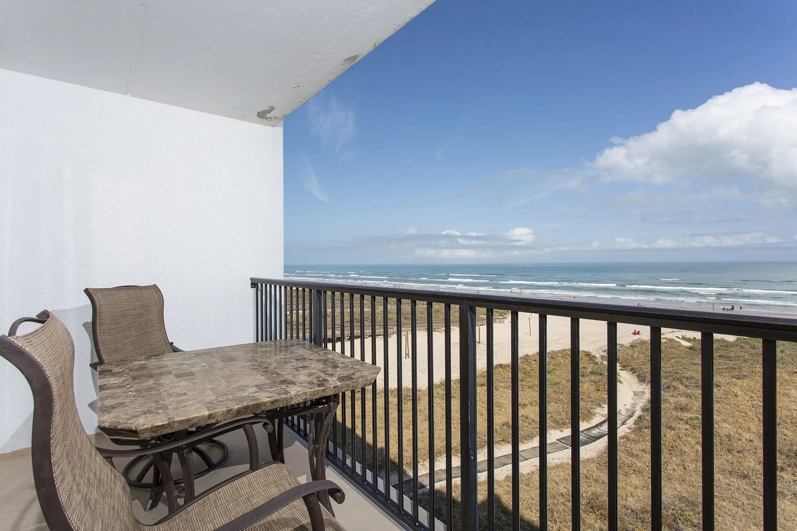 View from an Embassy Condominiums balcony over white sand and the Gulf of Mexico.